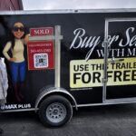 Lalla Fitzpatrick Associate Broker RE/MAX Plus standing beside her branded moving trailer offering free moving service to home buyers and sellers in Monroe County NY
